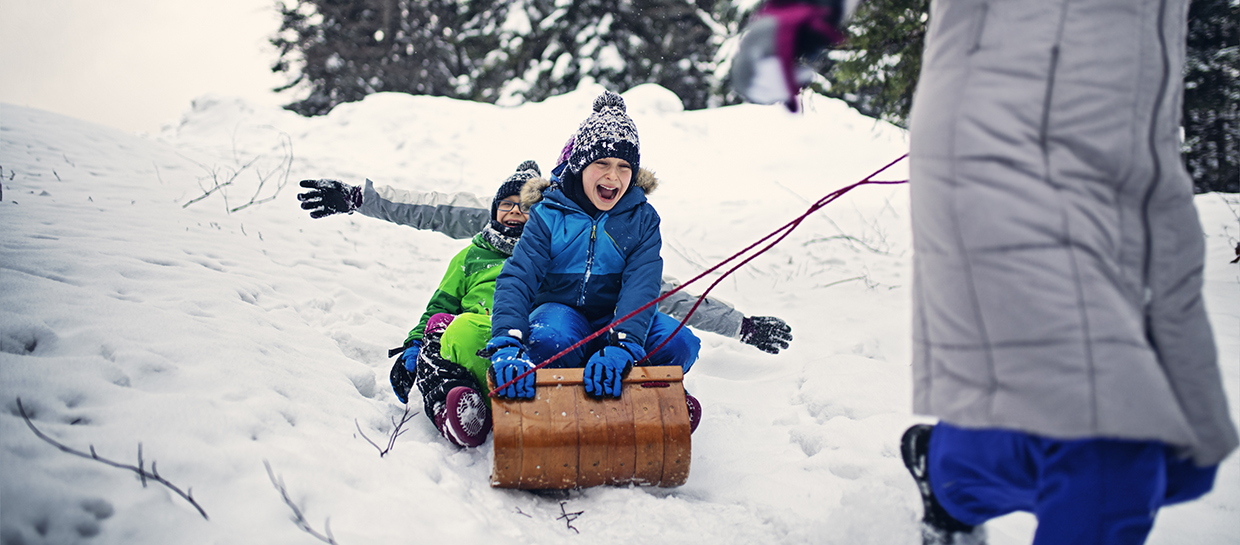 Three children being pulled on a toboggan 