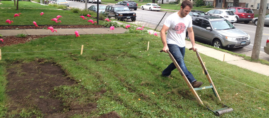 Man using a sod kicker on green lawn