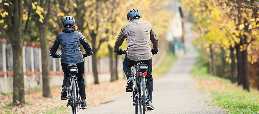 Two people biking together on a path in the fall