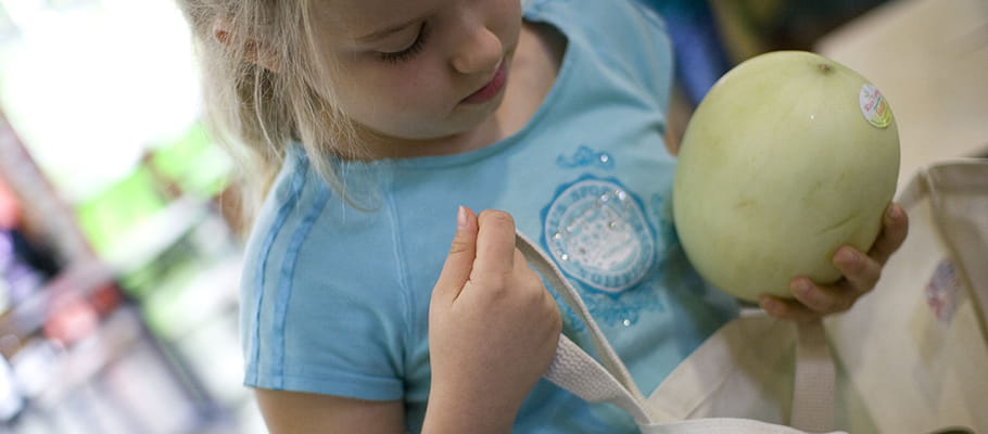 Girl putting melon in reusable bag