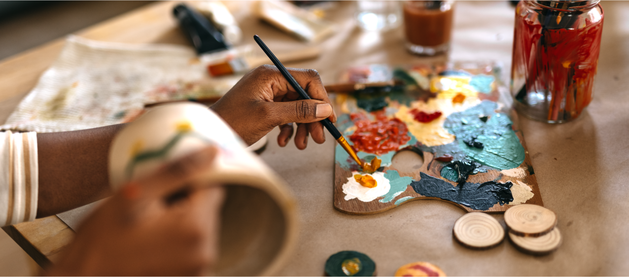 Close up of hands hand painting a ceramic mug