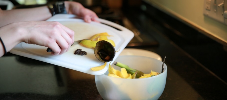 Close up of hands pushing organics scraps into bowl