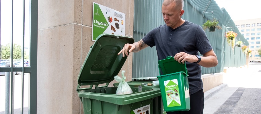 Man dropping organics bag into organics bin outside