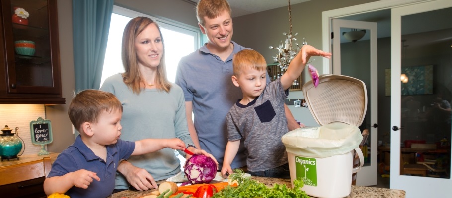 Family putting food scraps into organics bin in kitchen